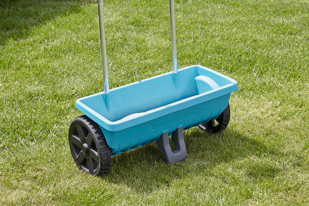 A GARDENA fertiliser spreader L on a green lawn.