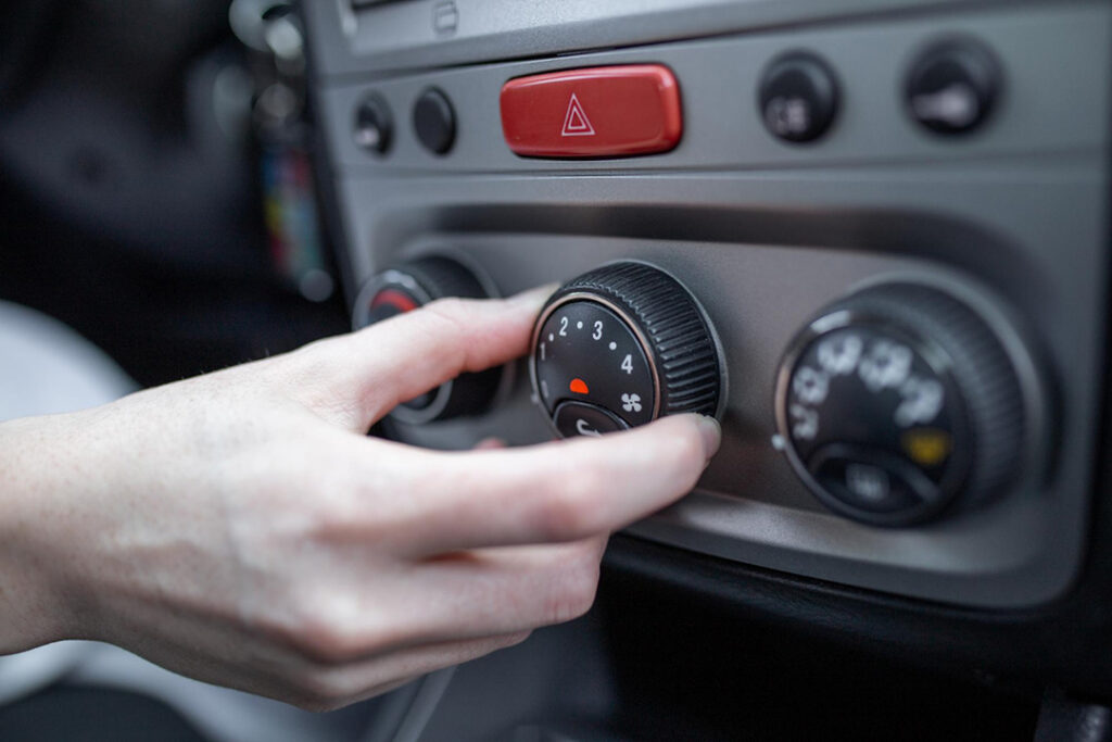 A close-up of a person's hand turning the heater dial inside their vehicle.
