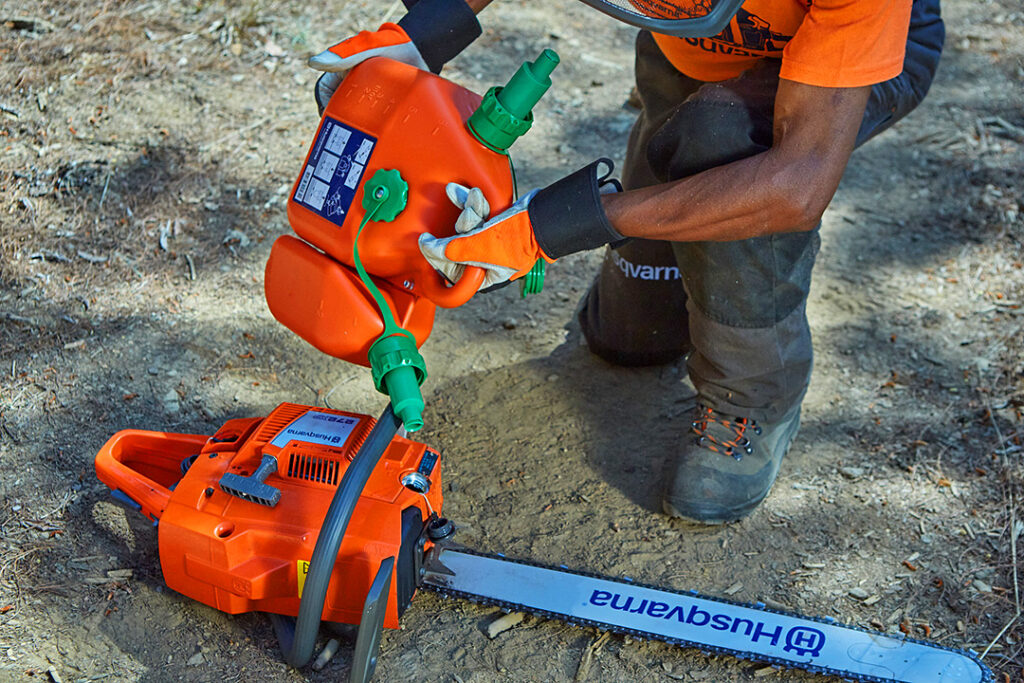 A forester uses a Husqvarna Combi Can to fill up his chainsaw with petrol.