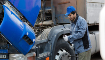 A man repairing the engine on a logistics lorry.