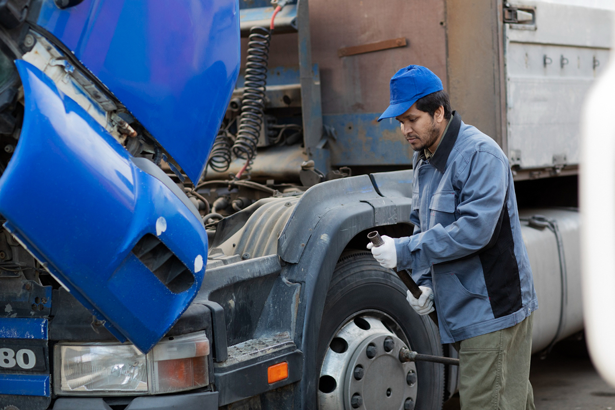A man repairing the engine on a logistics lorry.