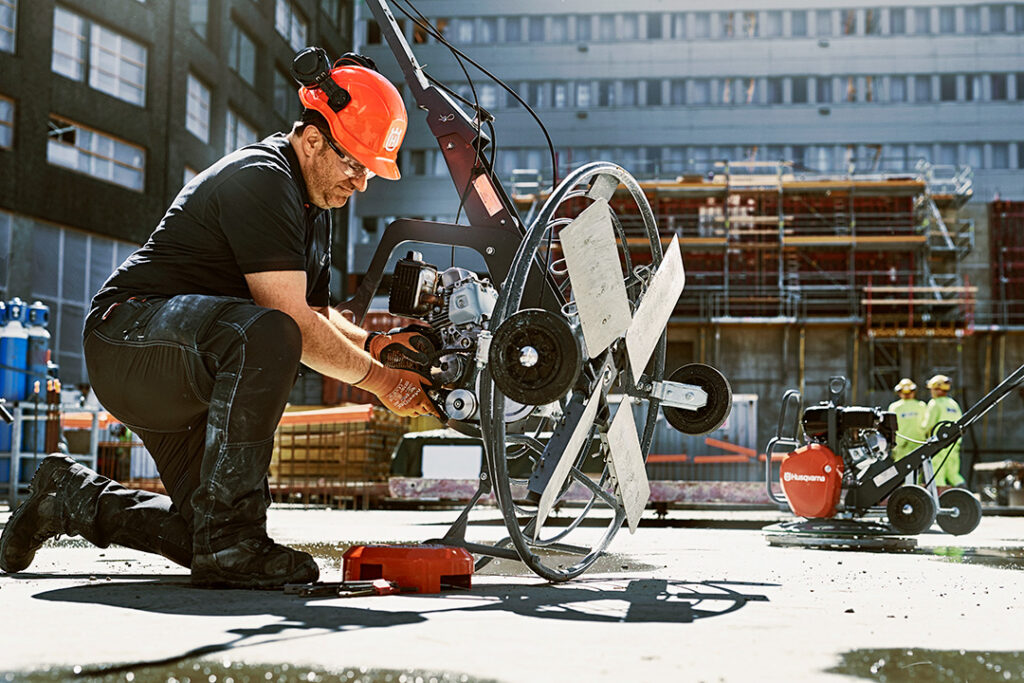 A man servicing a Husqvarna power trowel.