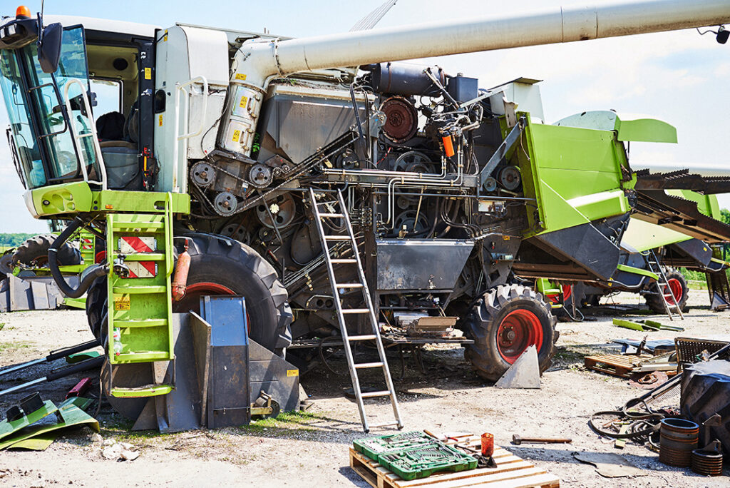 A green combine harvester undergoing maintenance.