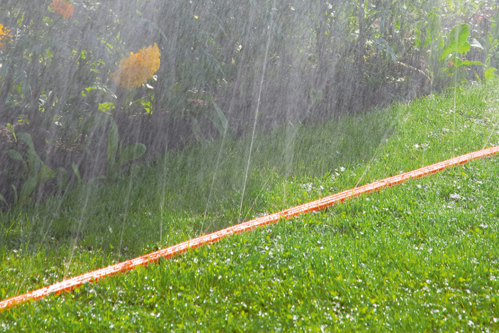 A GARDENA Sprinkler Hose on a green lawn.