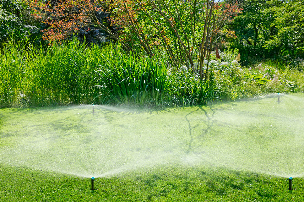 Four GARDENA pop-up sprinklers on a green lawn.