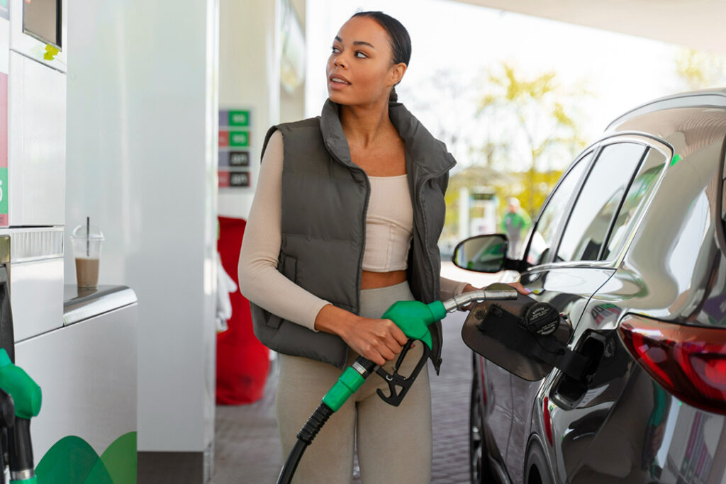 A woman fills up her SUV from a fuel pump.